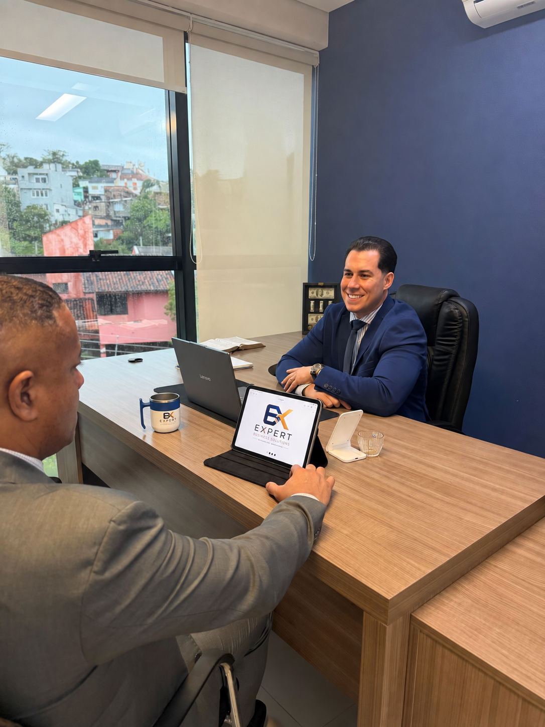 Juliano Massairo em reunião com cliente, analisando a marca Expert Business Solutions no tablet