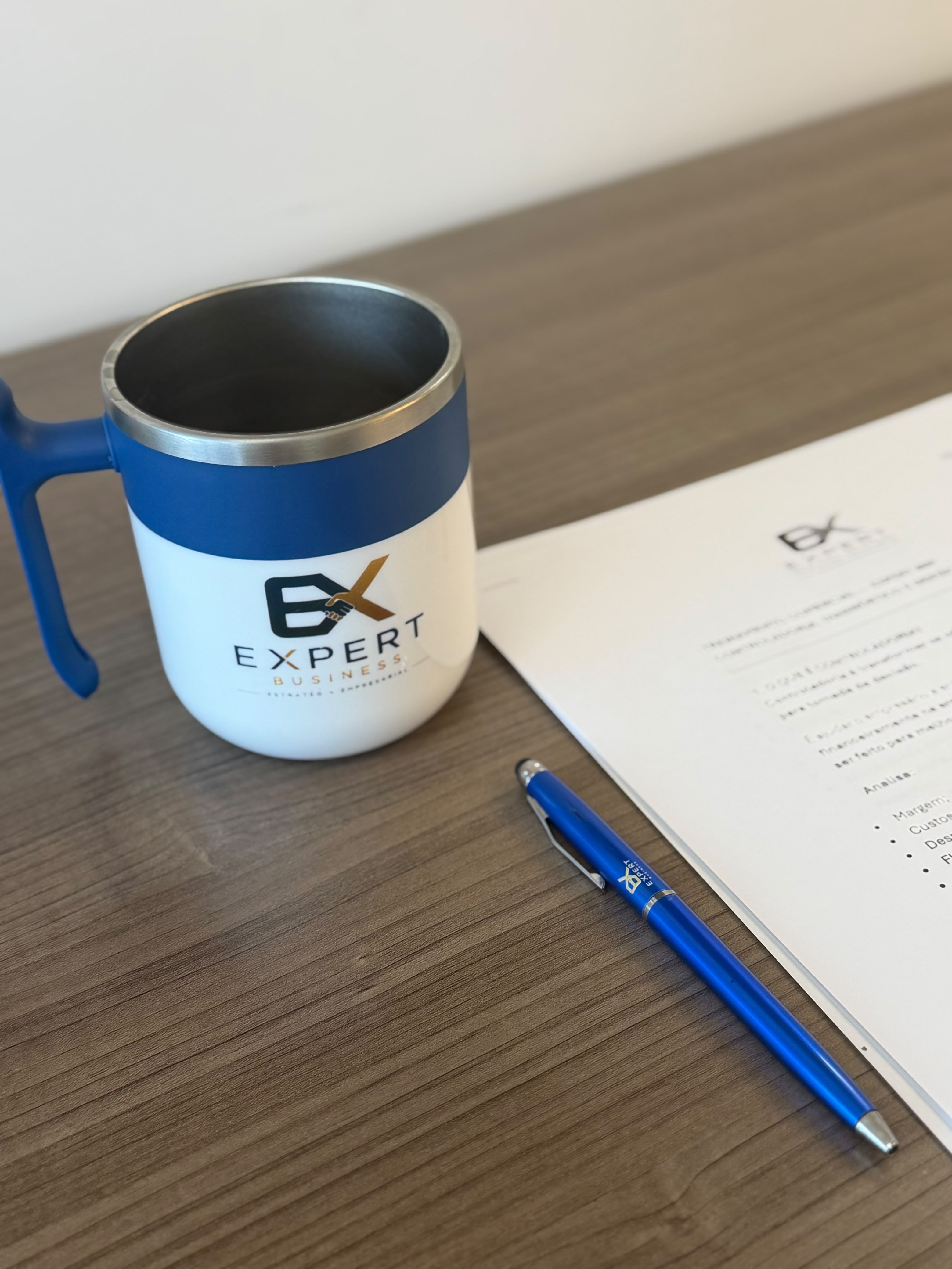 Caneca e caneta personalizadas da Expert Business Solutions sobre documento no escritório